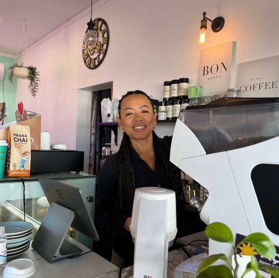A smiling barista behind the Culture Brew Mug coffee machine